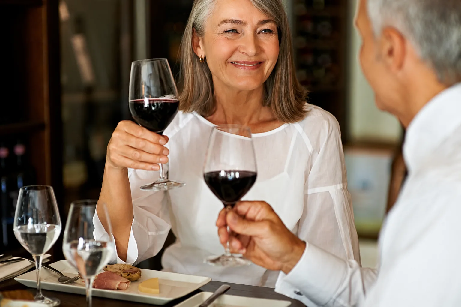 Seniorpar skålar med ett glas rött vin